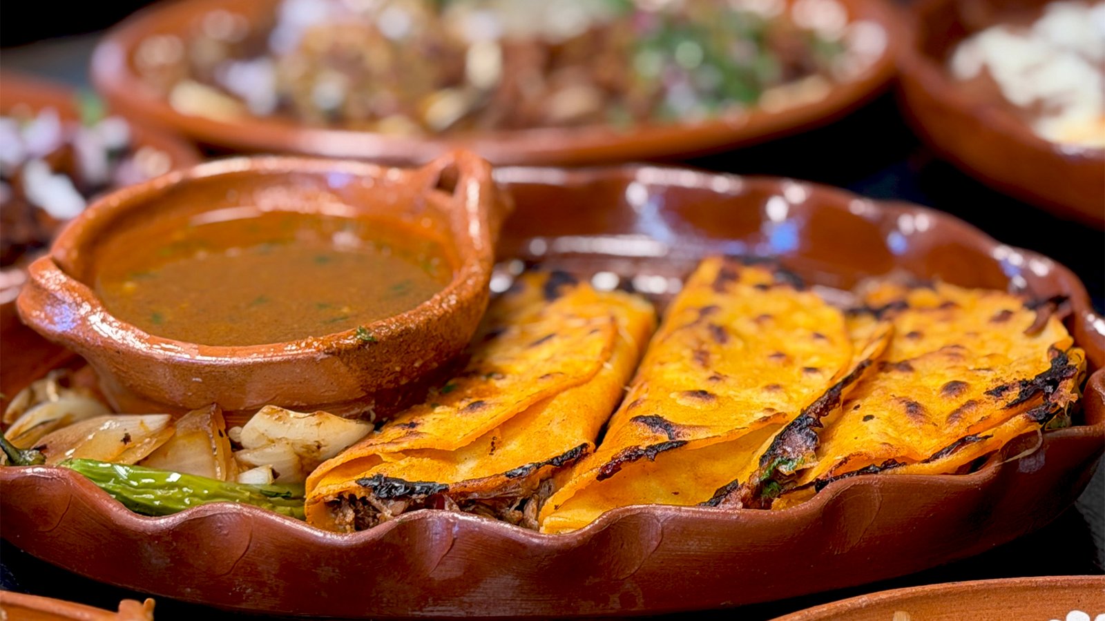Stacked quesabirria tacos with melted cheese and consommé at Taqueria Los Viejones